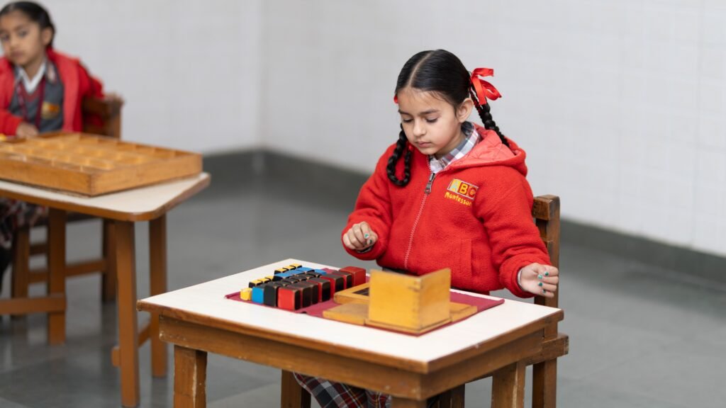 metal-roof A young girl in a classroom focused on a Montessori educational activity with colorful blocks.