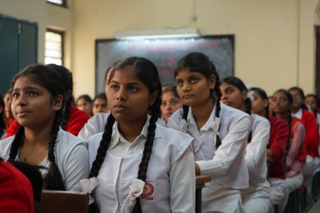 services-2 Group of Indian schoolgirls attentively listening in their classroom wearing uniforms.